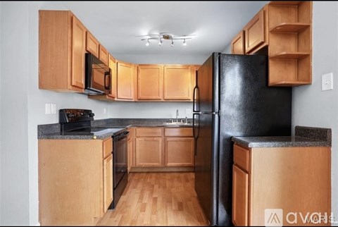 A kitchen with wooden cabinets and a black refrigerator.