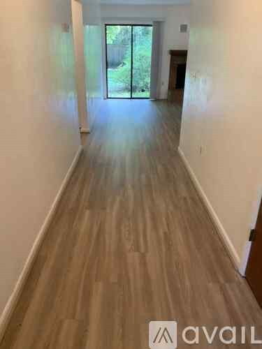 A long hallway with wooden floors and white walls.