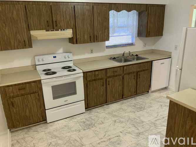 A kitchen with a white stove and brown cabinets.