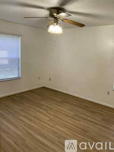 A room with a ceiling fan and wooden flooring.