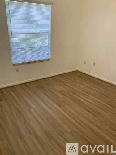 A room with wooden flooring and a window with blinds.