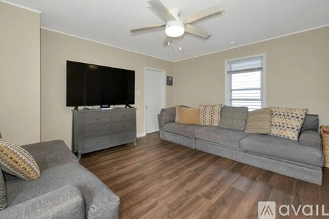 A living room with a grey couch and a television on a cabinet.