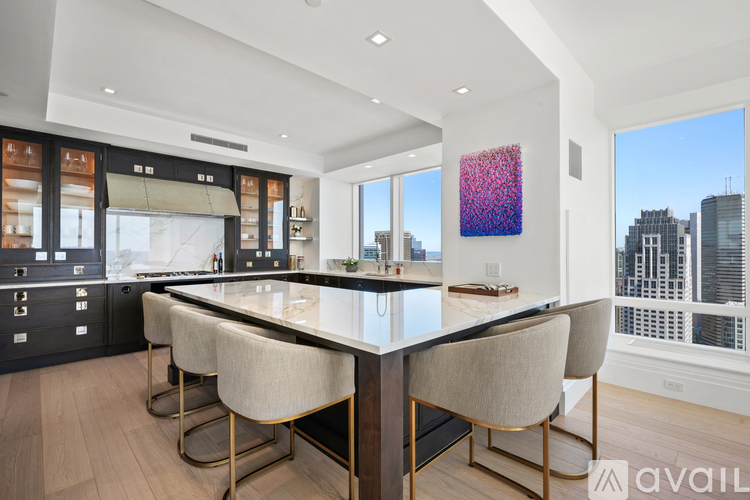 A modern kitchen with a large island and chairs.