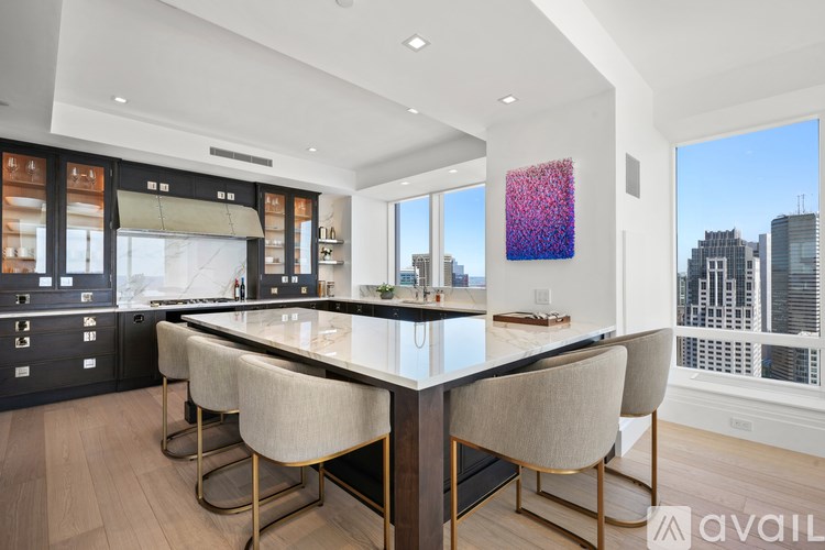 A modern kitchen with a large island and chairs.