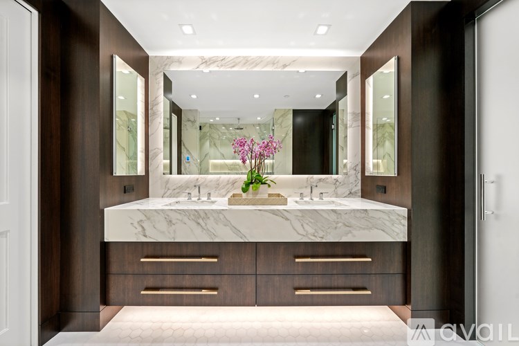 A bathroom with a marble countertop and wooden cabinets.