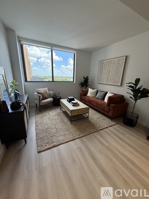 A living room with a large window, a couch, a chair, a coffee table, and a rug.