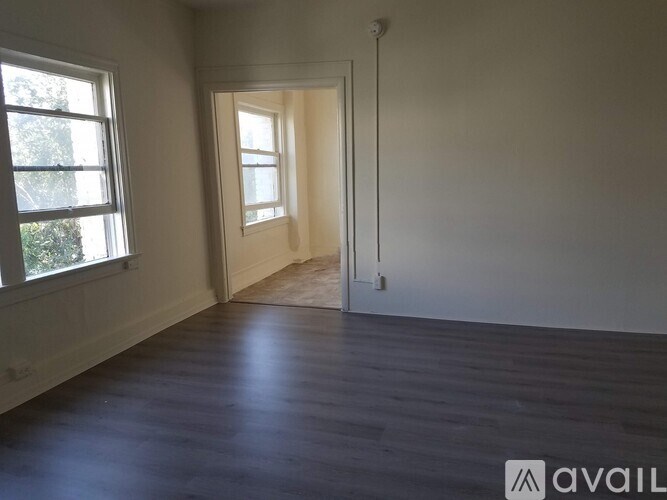 A room with wooden floors and two windows.
