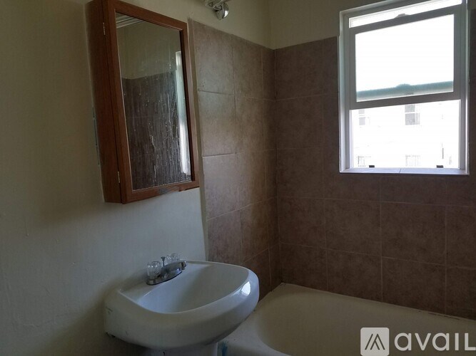 A bathroom with brown tiles and a white sink.