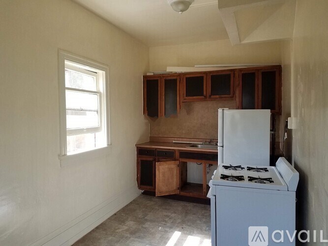 A kitchen area with a stove, cabinets, and a window.