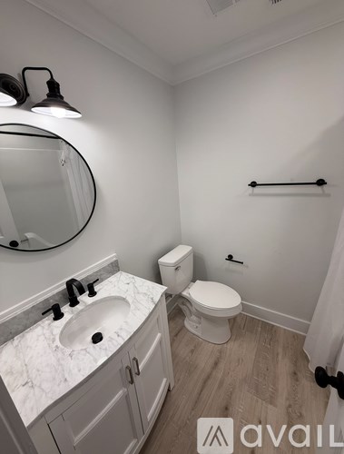 A bathroom with a toilet, sink, and mirror.