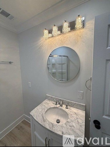 A bathroom with a marble sink and a round mirror.