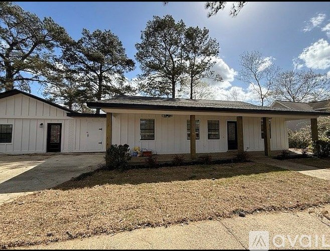 A white house with a black roof and a brown lawn in front.