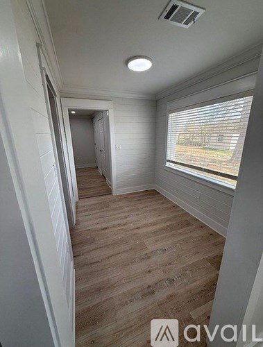 A room with wooden flooring and a window with blinds.