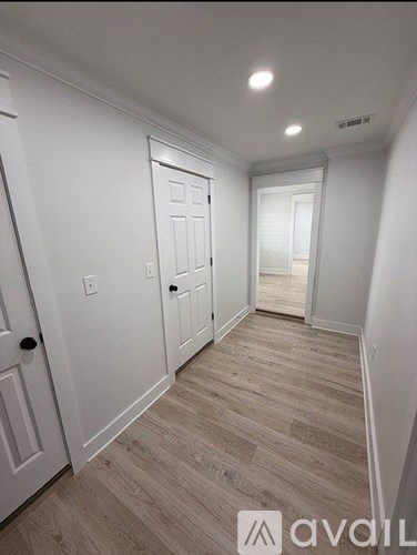 A hallway with wood flooring and white walls.