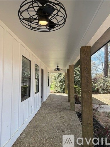 A long white hallway with a light on the ceiling and a window on the wall.