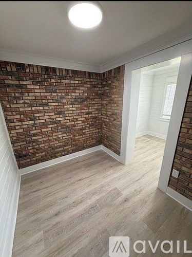 A room with a brick wall and wooden flooring.