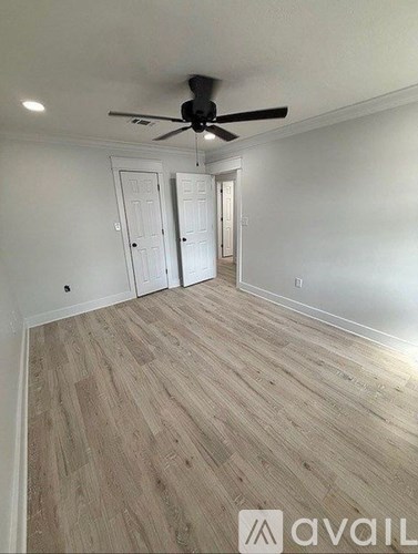 A room with a ceiling fan and wooden flooring.