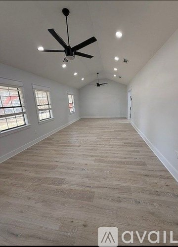 A spacious room with a ceiling fan and wooden flooring.