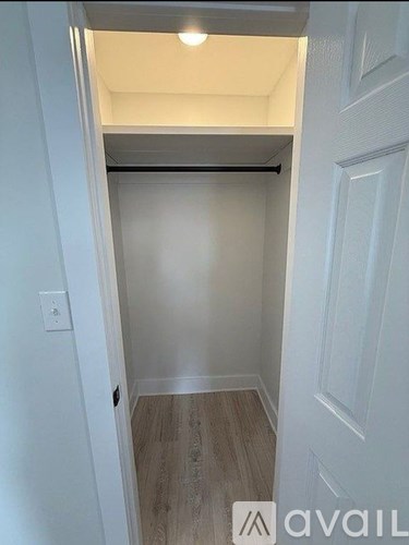 A small, empty room with a door on the right and a light switch on the wall.