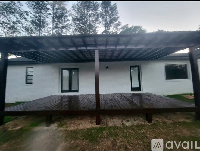 A white house with a wooden deck and a metal roof.