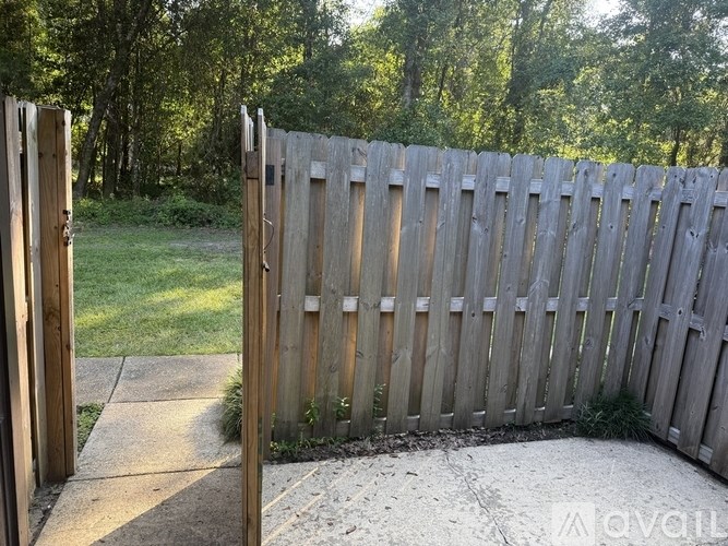 A wooden fence with a gate is in front of a grassy area.