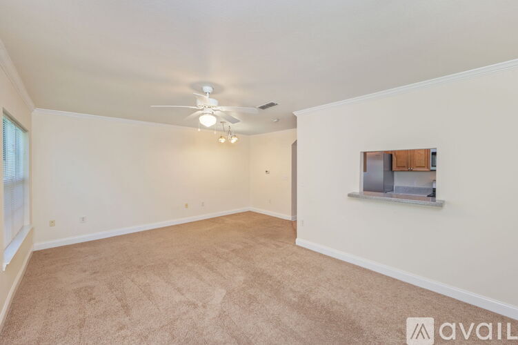 A spacious room with a ceiling fan and carpeted floor.