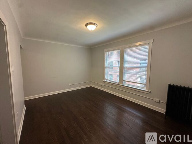 A room with wooden floors and a window with blinds.
