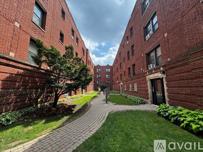 A brick building with a tree and a walkway in front.