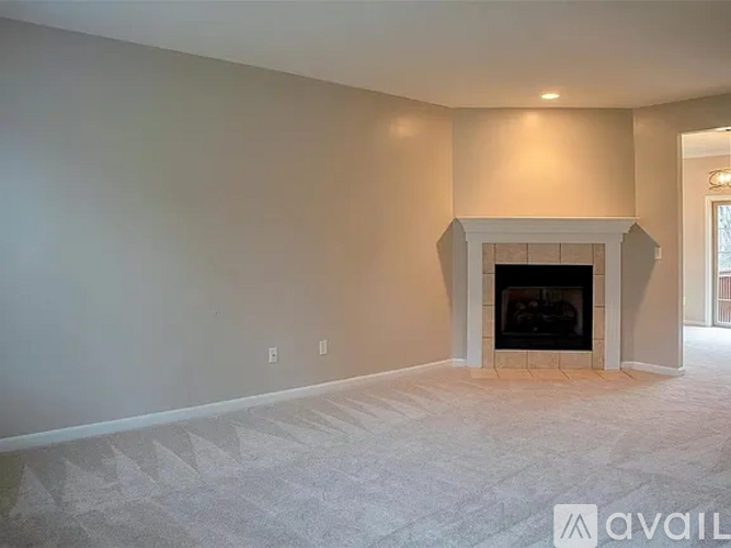 A spacious living room with a fireplace and a carpeted floor.