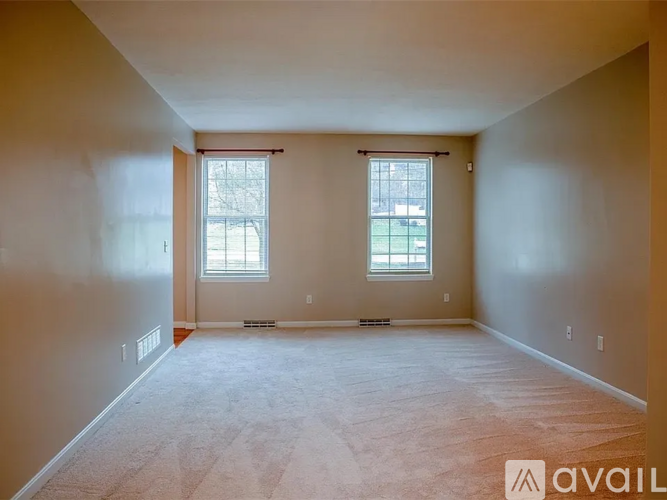 A spacious room with two windows and carpeted floor.