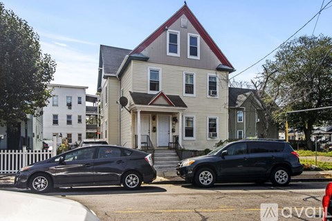 Two cars parked in front of a two-story house.