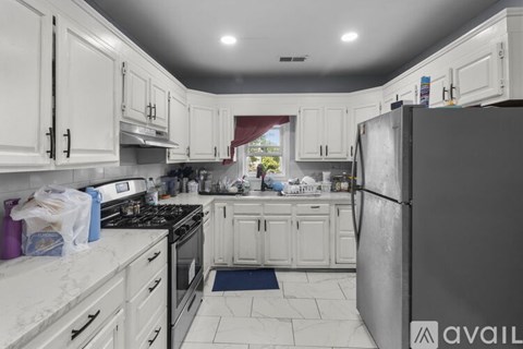 A kitchen with white cabinets and a black refrigerator.