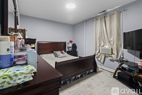 A bedroom with a bed, a dresser, and a window with curtains.
