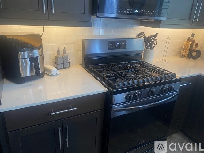 A modern kitchen with a black stove and a black coffee maker.