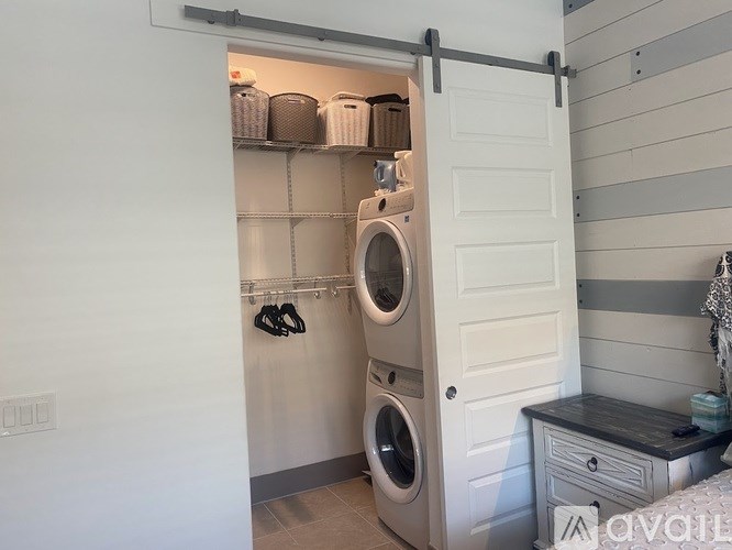 A laundry room with a washer and dryer, a shelf with storage boxes, and a white door.