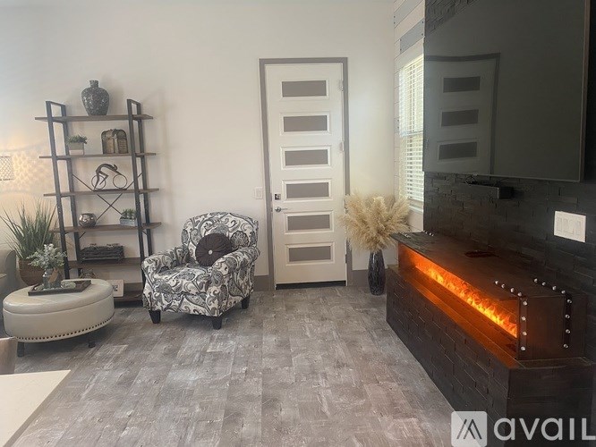 A modern living room with a grey carpet, a white chair, a wooden shelf, and a fireplace.