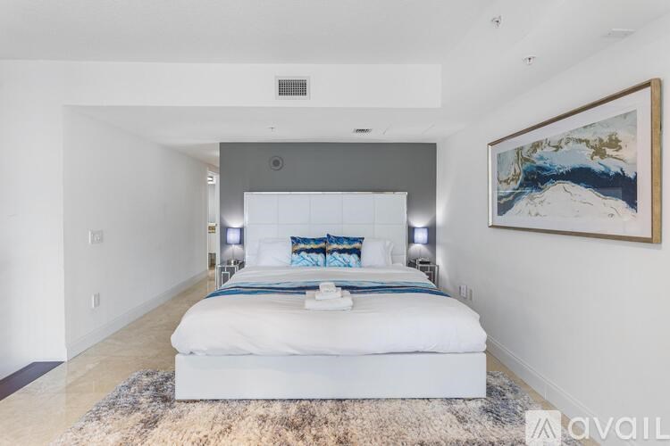 A bedroom with a large bed and a painting on the wall.