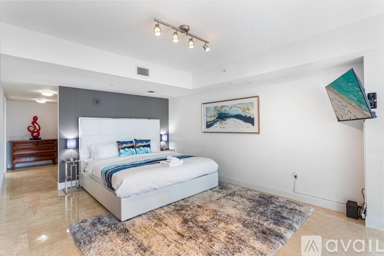 A bedroom with a large bed and a painting on the wall.