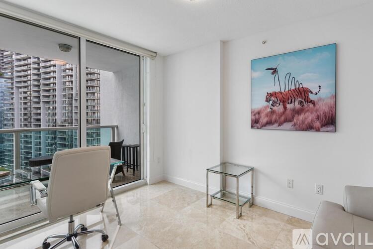 A room with a chair, a glass table and a painting of a tiger.