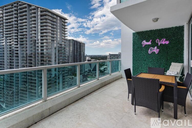 A balcony with a table and chairs overlooks a cityscape.
