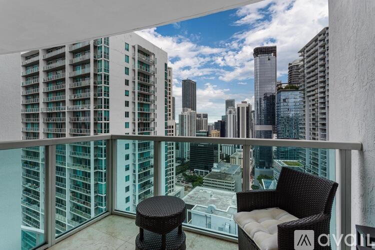 A balcony with a chair and table overlooking a cityscape.