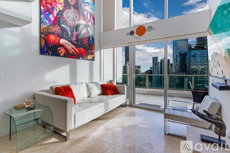 A living room with a white couch and a large painting on the wall.