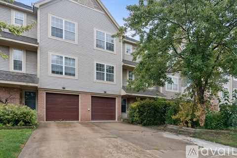 A two-story building with a garage door is surrounded by greenery.