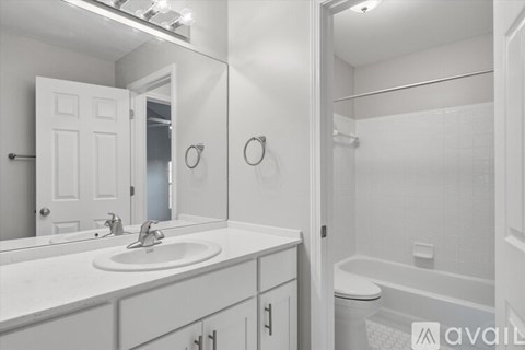 A room with a black fridge and a table with a plant on it.