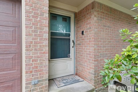 A glass door with a white frame is set in a brick wall.