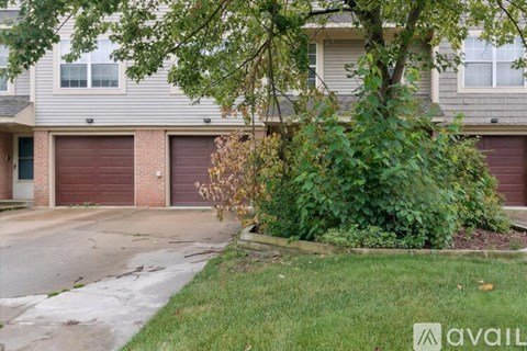 A tree in front of a grey building with two garage doors.