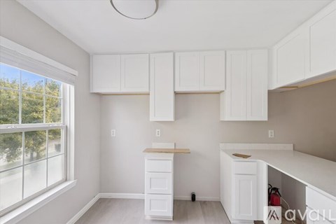 A kitchen with white cabinets and a window.