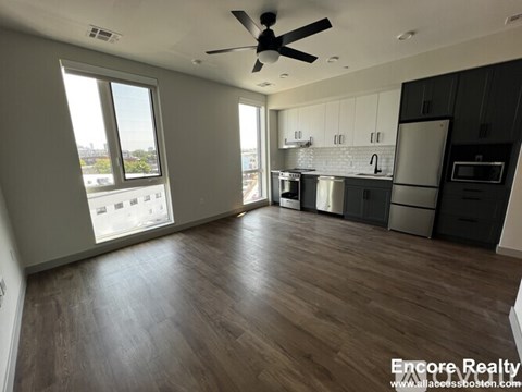 A spacious kitchen with dark wood floors and a ceiling fan.