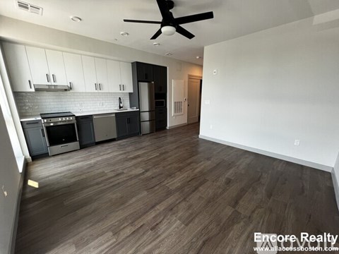 A spacious kitchen with dark wood floors and white walls.