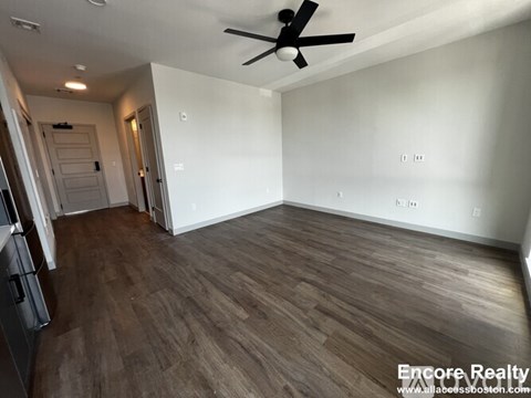 A room with a ceiling fan and wooden flooring.